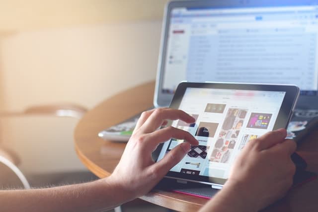 A person browsing a shopping feed on an ipad or tablet, with the big iMac in the background